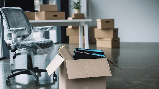Office items packed into boxes with a wrapped desk chair ready for moving