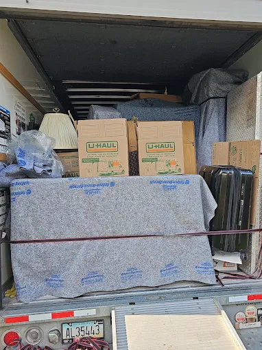 Movers loading cardboard boxes into a moving truck at dusk